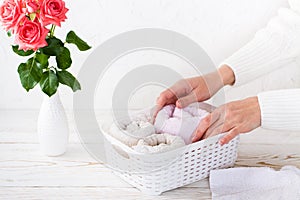 Women`s hands neatly fold towels into a basket. Organization and order