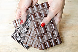Women's hands, offering a choice of different chocolate bars - black, milk and porous chocolate