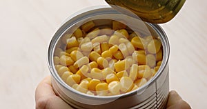 Women's hands open a can of corn. Canned food closeup.
