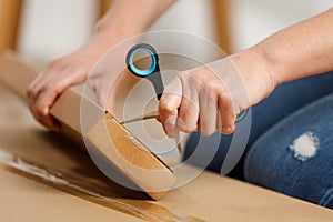 Women's hands open a cardboard box with scissors, a parcel