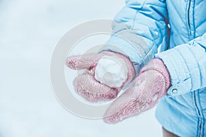 Women`s hands in pink mittens make a snowball for outdoor play in the winter in the forest, Toned and matte