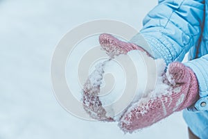 Women`s hands in pink mittens make a snowball for outdoor play in the winter in the forest, Toned and matte