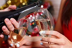 Women`s hands pouring champagne into glasses, close up. Celebrat