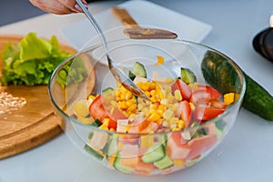 Women`s hands prepare a dietary salad with herbs on the background of a light kitchen