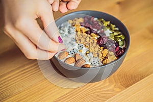 Women`s hands are preparing a smoothie bowl