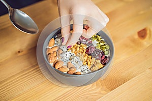 Women`s hands are preparing a smoothie bowl