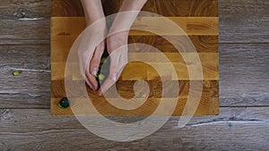 Women`s hands removed from wooden board sliced cucumbers