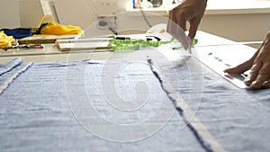 Women`s hands of seamstresses make markings on the pattern using a special chalk and ruler. Sewing workshop, toy factory