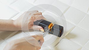 Women's hands sharpen a knife on a modern home sharpener and try the sharpness of the knife