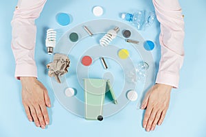 Women`s hands sort the waste. Ecology concept, a lot of recyclable objects in containers on the color background. Copy space for