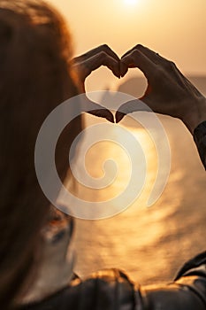 Women`s hands symbol of the heart lifestyle and feelings concept with sunset light nature on a winter background. Valentine`s da