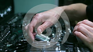 Women's hands take out a part from a set of car tools.