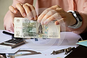Women`s hands tear ten rubles at a table with reports, default in Russia due to sanctions, collapse of the ruble
