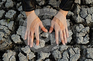 Women's hands touch the dried cracked earth