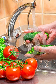 women`s hands washing vegetables in the kitchen