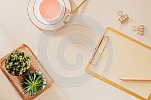 Women`s home office workspace with clipboard, macaroons, pen, coffee mug on pastel background. Flat lay, top view lifestyle