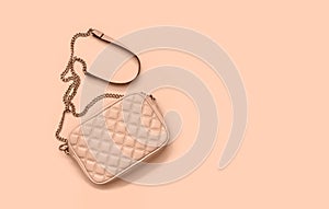 Women`s leather bag with a gold chain. Fashion color of the season peach gelato. Flat lay. Copy space