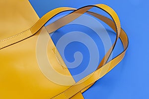 Women`s leather handbag of yellow color on a blue background. No name, no logo