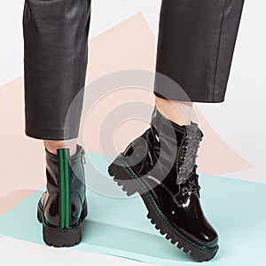 Women& x27;s legs in black pants and black short shoes on medium heel stands in the studio against a colored background