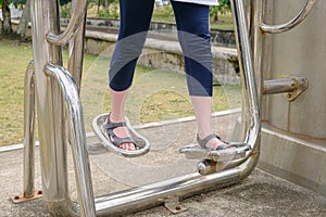 Women's legs on an outdoor metal simulator that imitates walking photo