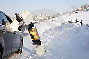 Women,s legs in snowboard from the car near beauty view of mountains and christmas trees in winter