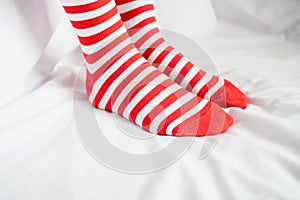 Women`s legs in socks colors alternating, side stand on white fabric floor.