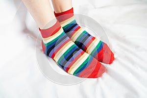 Women`s legs in socks colors alternating, side stand on white fabric floor.