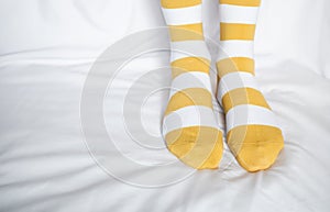 Women`s legs in socks colors alternating, side stand on white fabric floor.