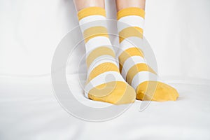 Women`s legs in socks colors alternating, side stand on white fabric floor.