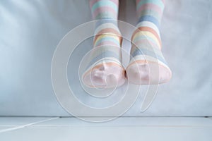 Women`s legs in socks colors alternating, side stand on white fabric floor.