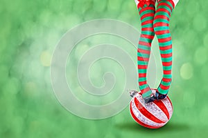 Women`s legs in striped stockings stand on a red Christmas background