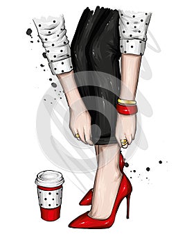 Women`s legs in stylish jeans and high-heeled shoes. A glass of coffee. Fashion and style, clothing and accessories.