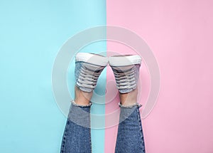 Women& x27;s legs in tight, torn jeans, sneakers on pink blue pastel background. Top view, minimalism, copy space.