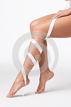 Women`s legs with white ribbon