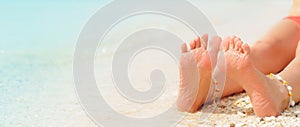 Women`s legs on the white sand beach summer vacation