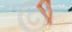 Women`s legs on the white sand beach summer vacation