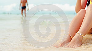 Women`s legs on the white sand beach summer vacation