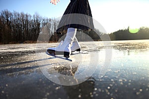 Women's legs in white skates on an outdoor ice rink. ... People, winter sport and leisure concept.