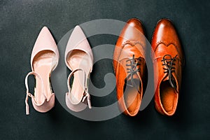 Women`s and men`s shoes on a black background. Wedding accessories for the bride and groom. Fashionable shoes. Top view, flat