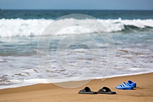 Women's and Men's Slippers on a Sandy Ocean Beach