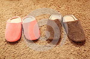 Women`s and men`s slippers standing on the carpet. Two pairs of house shoes