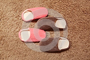 Women`s and men`s slippers standing on the carpet. Two pairs of house shoes