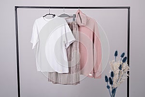 Women\'s minimal fashion pastel clothes. Stylish female t-shirts  hoodie  pants on hanger on white background. Fashion blog