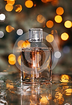 Women`s perfume on golden bokeh background with water drops and reflection.close-up fragrance shot with christmas background,