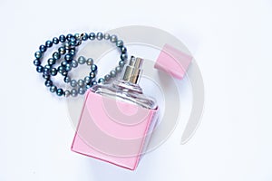 Women`s perfume and pearl beads on a white background