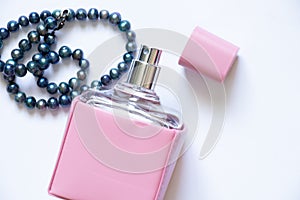 Women`s perfume and pearl beads on a white background