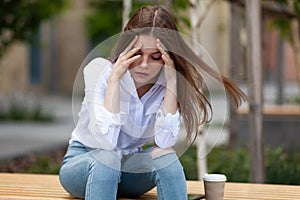 Women`s problems. Upset girl sits outdoors. Burnout, mental trauma