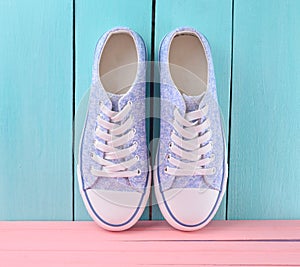 Women& x27;s retro hipster sneakers with white laces on a pink wooden floor against a blue wooden wall background