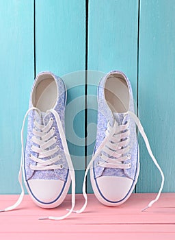 Women& x27;s retro hipster sneakers with white laces on a pink wooden floor against a blue wooden wall background