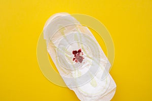 Women's sanitary pad with blood on a yellow background close-up